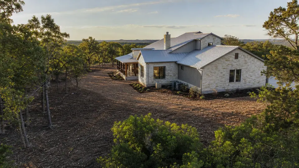 Defensible space cleared and mulched around a stone ranch home in North Texas